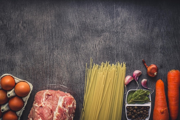 Raw meat beef with spaghetti, fresh organic vegetables, onion, garlic, spices, peppercorns, rosemary, salt and dill for cooking pasta. Top view.