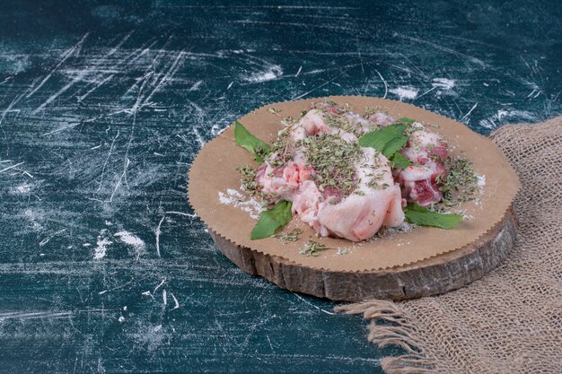 青に新鮮な乾燥ハーブを添えた生肉片。