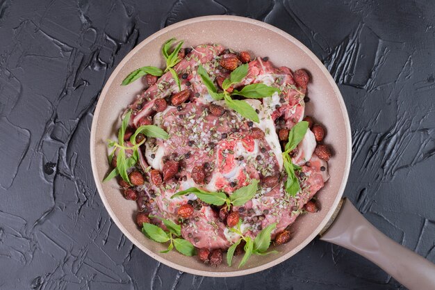 Raw meat salad with fresh mint in pan on dark surface.