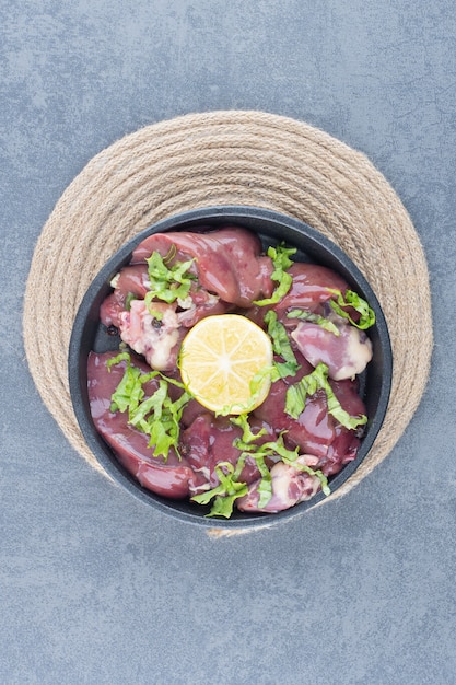 Foto gratuita fette di carne cruda e limone a fette sulla banda nera.