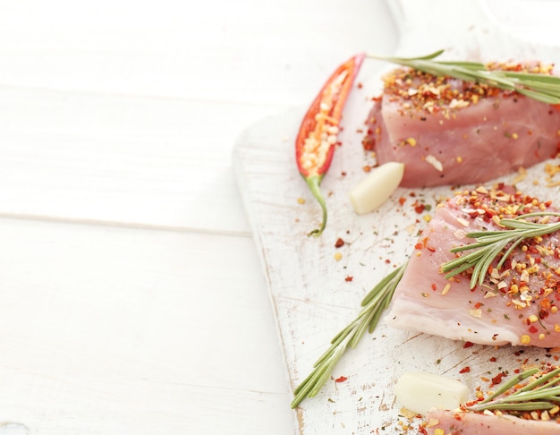 Raw meat with herbs and spices on a white board