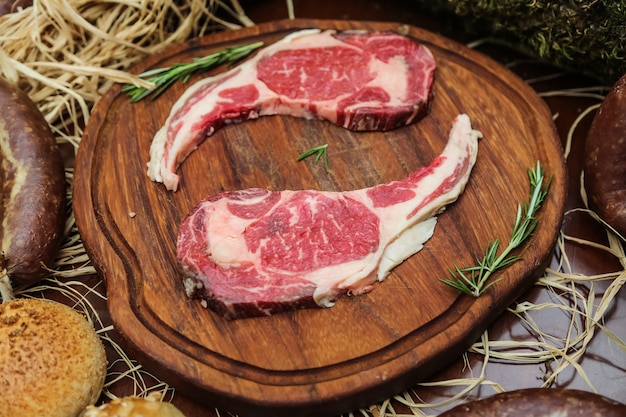 Raw meat on the wooden board with herbs