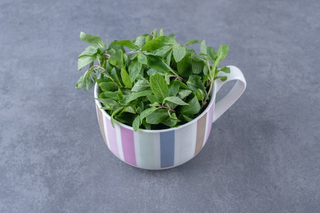 Raw mint in a cup , on the marble surface.