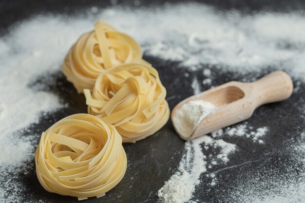 Raw nest noodles with flour on black.