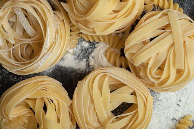 Raw nest noodles with flour on black.