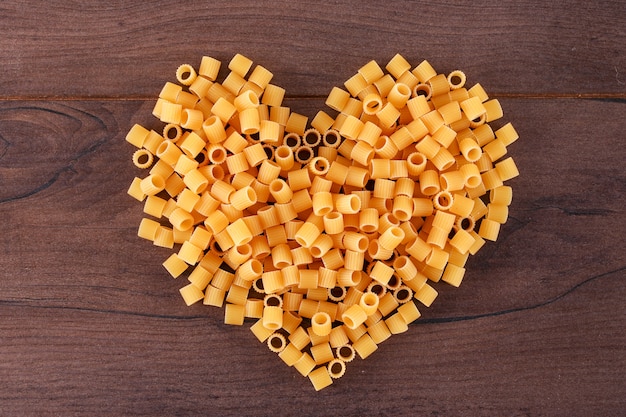 raw pasta in heart shape top view on wooden surface