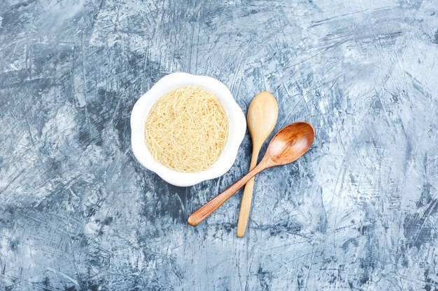 無料写真 灰色の漆喰の背景に木のスプーンの上面図と白いプレートの生パスタ