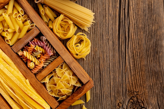 Free photo raw pasta mix on wooden background with copy space