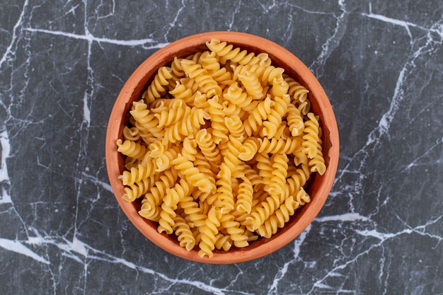 Penne di pasta cruda in ciotola di ceramica.