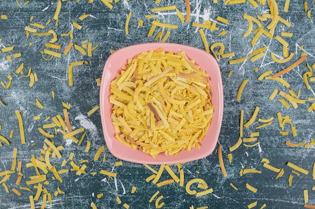 Pasta cruda in una ciotola rosa su sfondo blu. foto di alta qualità