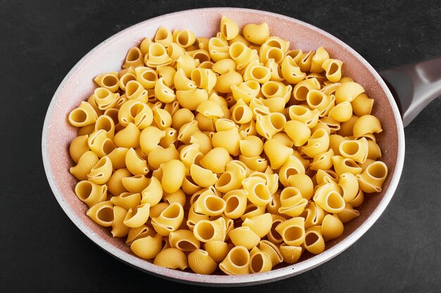 Raw pasta in a pink skillet.