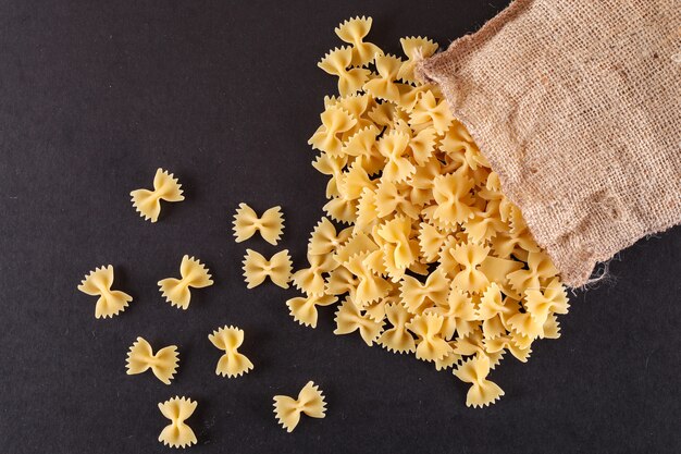 Free photo raw pasta in sackcloth on black table