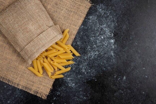 Raw pasta varieties on a piece of burlap.