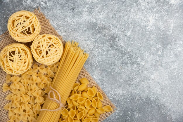 Raw pasta varieties on a piece of burlap.