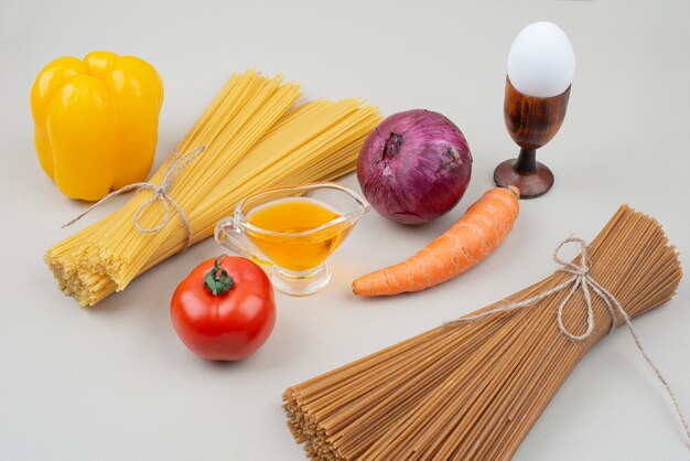 Raw pasta with vegetables on white background. High quality photo