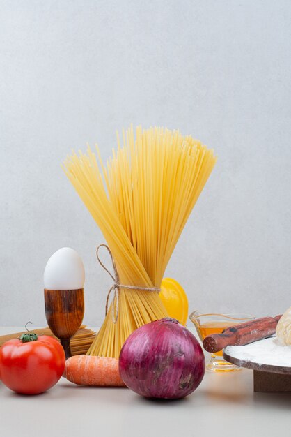 Raw pasta with vegetables on white.