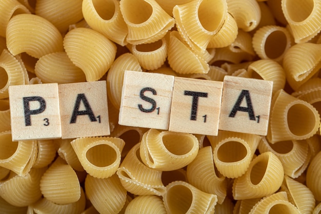 Foto gratuita pasta cruda con lettere in legno.