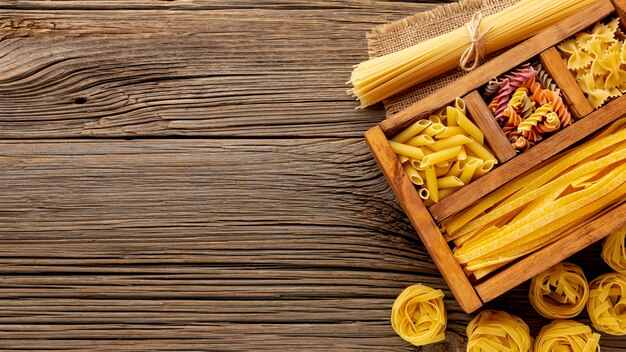 Raw pasta in wooden box with copy space