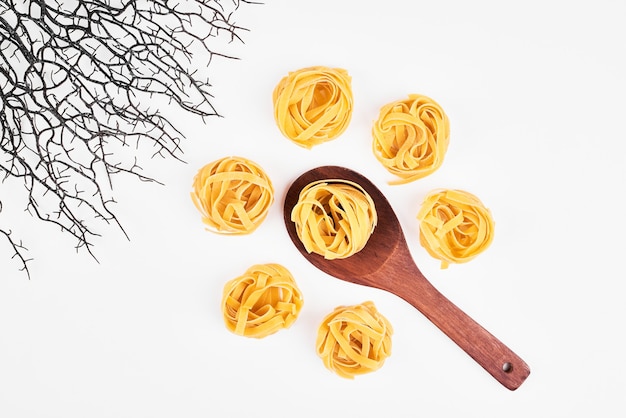 Raw pasta in a wooden spoon, top view.