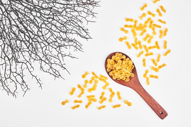 Raw pasta in a wooden spoon on white