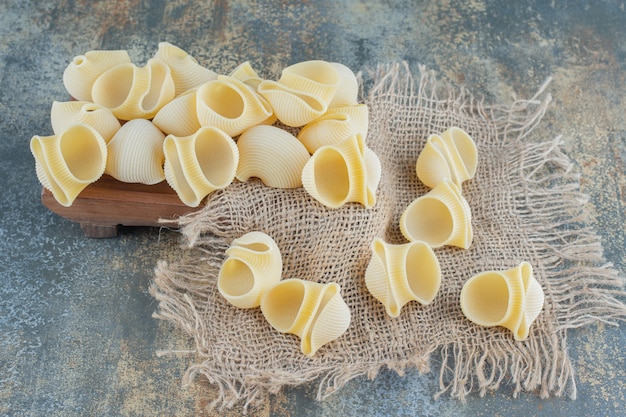 Free photo raw pastas on trivet, on the marble surface.