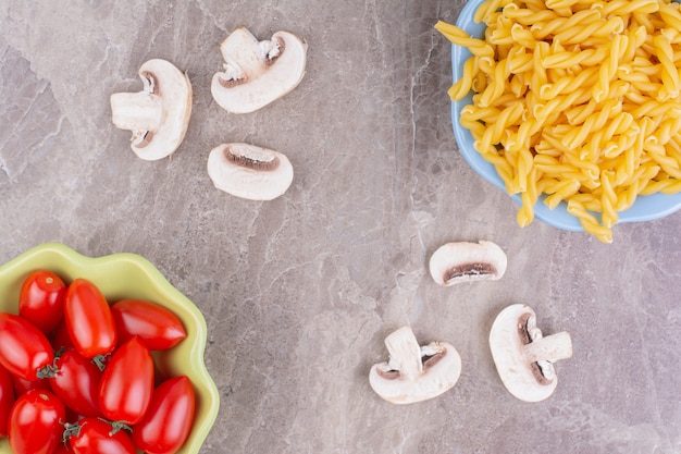 Raw pastas with cherry tomatoes on a marble space. 