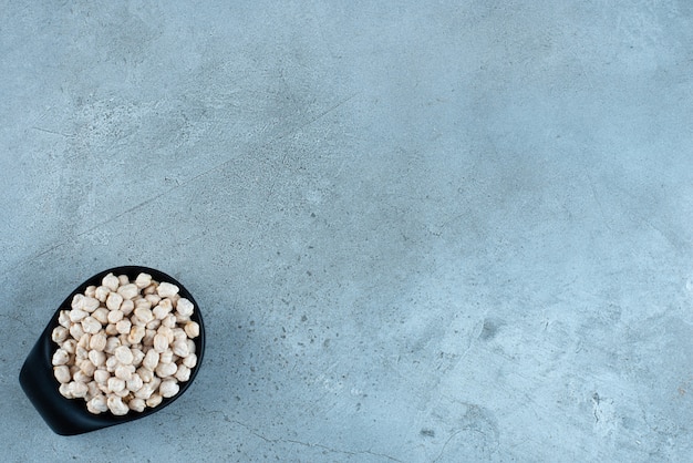 Raw pea beans in a black cup on blue background. High quality photo