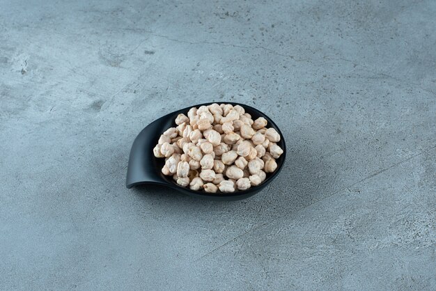 Raw pea beans in a black cup on the ground. High quality photo