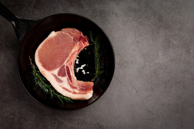 Raw pork chop steak on the dark surface.