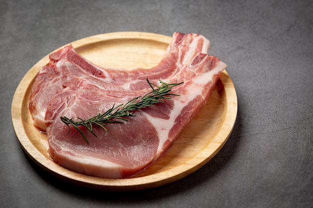 Raw pork chop steak on the dark surface.