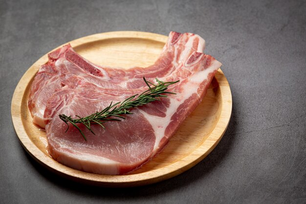 Raw pork chop steak on the dark surface.