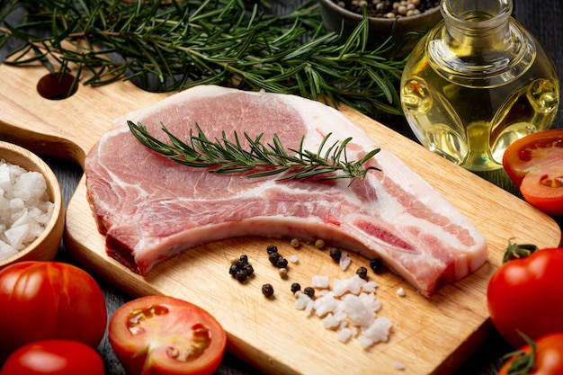 Raw pork chop steak on the dark wooden surface.