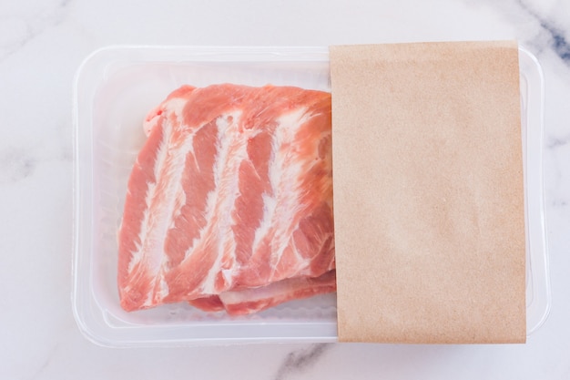 Raw pork ribs in vacuum packaging on marble background, logo mockup for design. Premium Photo