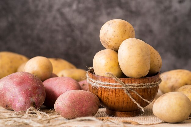 Raw potatoes in wooden bowl