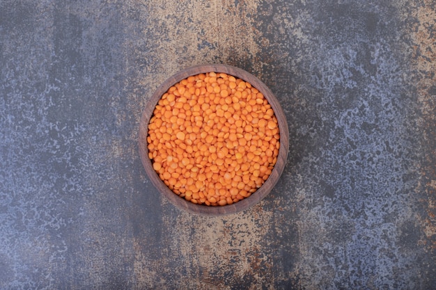 無料写真 青いテーブルの上の木製のボウルに生の赤レンズ豆。