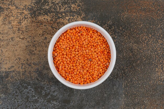 Raw red lentils in white bowl. 