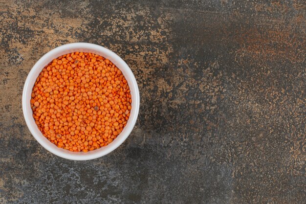 Raw red lentils in white bowl. 