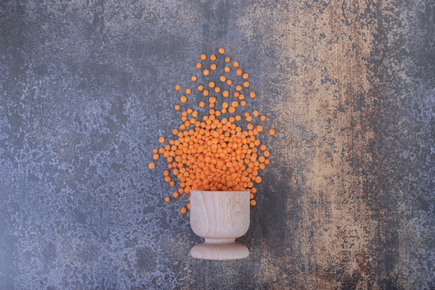 Free photo raw red lentils in wooden bowl on blue background.