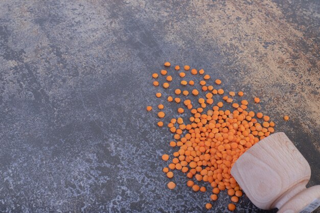 Raw red lentils in wooden bowl on blue background.