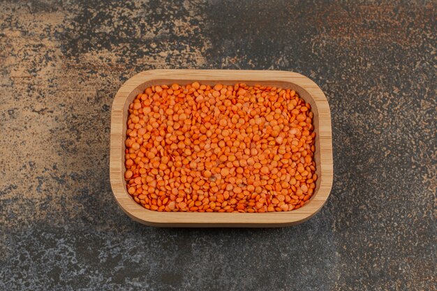 Raw red lentils on wooden plate. 