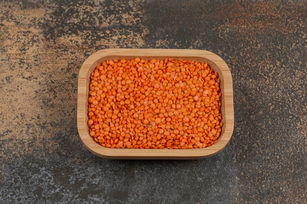 Raw red lentils on wooden plate. 