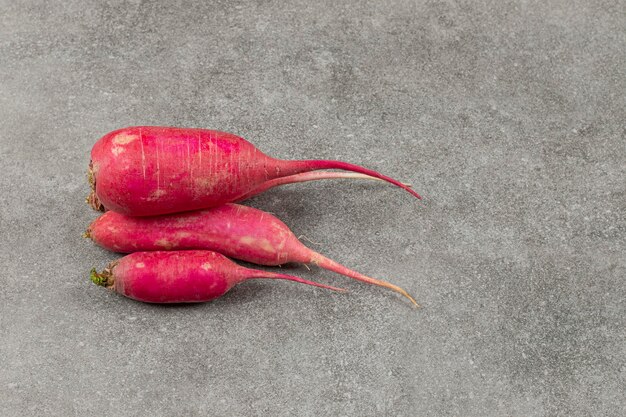 Raw red radishes on marble surface