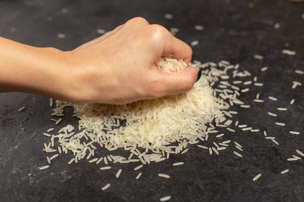 Free photo raw rice granules taking by female on dark