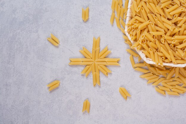 Raw rigatoni pasta in white bowl