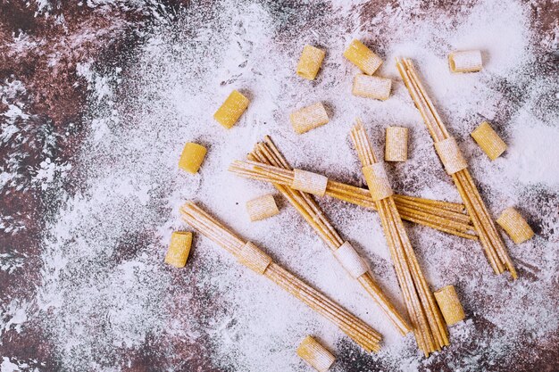 Raw spaghetti and macaroni on powdery wooden table. 