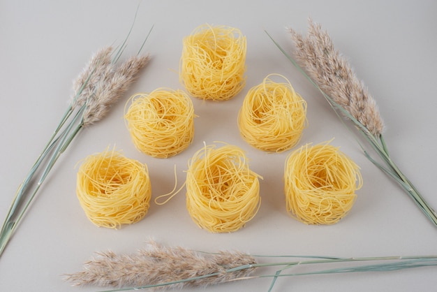 Foto gratuita nidi di spaghetti crudi su bianco con grano.