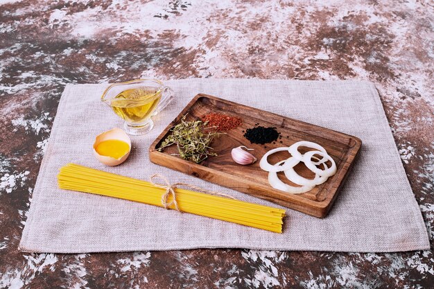 Raw spaghetti with fresh herbs on tablecloth. 