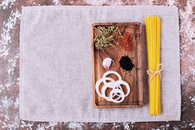 Raw spaghetti with fresh herbs on wooden table. 