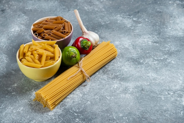 Сырые спагетти с овощами на деревянной доске.