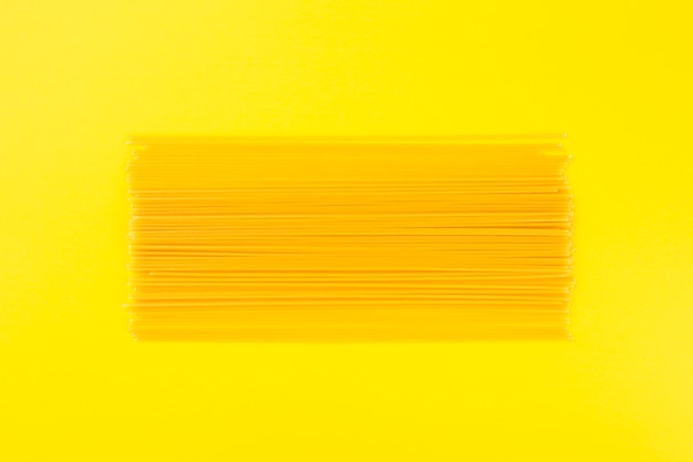Сырые спагетти на желтом фоне